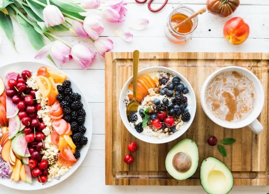cutting board with a bowl of colorful fruits and avocado cut in half